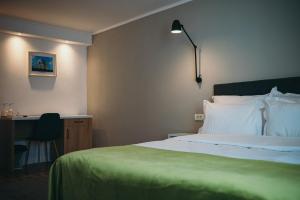 um quarto com uma cama, uma secretária e um candeeiro em Nest Guesthouse em Drobeta-Turnu Severin