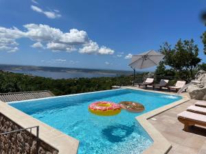 a swimming pool with an umbrella and two inflatables at Lovely Holiday Home in Starigrad with Private Swimming Pool in Starigrad-Paklenica