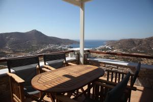 a wooden table and chairs on a balcony with a view at Skopelitis Village in Katapola