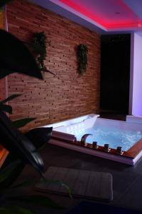 a jacuzzi tub in a room with a brick wall at Spa privatif by XELA in Auxerre