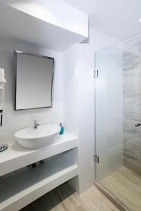 a white bathroom with a sink and a mirror at The Palms novasithonia in Vourvourou
