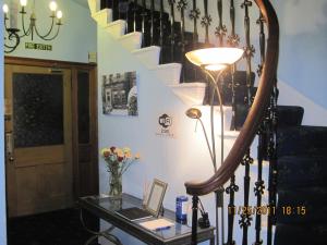 a room with a table with a lamp and stairs at Amaryllis Guest House in Edinburgh