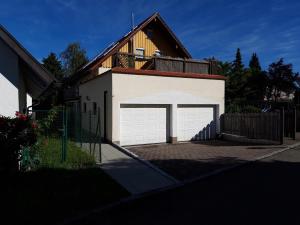 un garaje con una puerta de garaje blanca delante de una casa en Ferienwohnung am Argental, en Wangen im Allgäu
