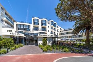 a building with a palm tree in front of it at Thalazur Saint Jean de Luz - Hôtel & Spa in Saint-Jean-de-Luz