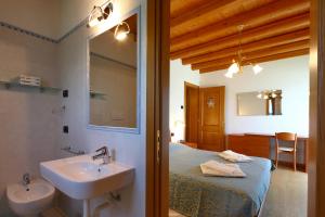 baño con lavabo y cama con espejo en Agriturismo Moro Barel, en Vittorio Veneto