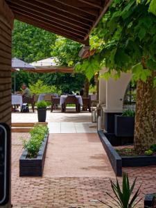 un patio al aire libre con mesas, sillas y árboles en Hotel Au Bon Coin du Lac en Mimizan