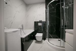 La salle de bains en noir et blanc est pourvue de toilettes et d'une douche. dans l'établissement Oxygen apartament nr 4, à Mielec