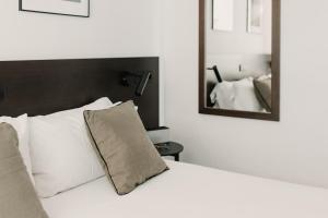a white bed sitting in a bedroom next to a mirror at Parker The Urban Flats in Valencia