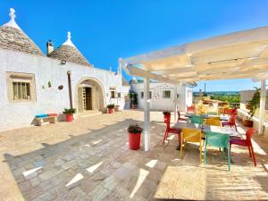 un patio con mesa y sillas bajo una sombrilla blanca en Trulli Fenice, en Martina Franca