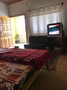 a living room with a couch and a television at ViveGee Cottage Khanipur Ayubia in Ayubia
