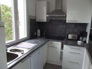 eine Küche mit weißen Schränken, einem Waschbecken und einem Fenster in der Unterkunft LE BELVEDERE 1- Front de Mer - Plage Argelès in Argelès-sur-Mer