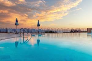 a swimming pool at sunset with the ocean in the background at Residence Pala Stiddata with panoramic swimming pool in Trinità d'Agultu e Vignola