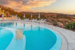 a swimming pool with chairs and a mountain in the background at Residence Pala Stiddata with panoramic swimming pool in Trinità d'Agultu e Vignola