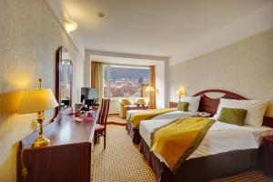 ブラショヴにあるホテル アロ パレスのベッド2台と窓が備わるホテルルームです。