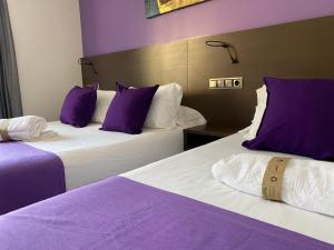 two beds with purple and white pillows in a room at Hotel TossaMar in Tossa de Mar +85 photos