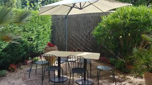 een tafel en stoelen onder een parasol in een tuin bij Charmant studio à Nyons. in Nyons