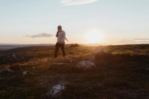 a man standing on top of a hill at sunset at Lapland Hotels Riekonlinna in Saariselka
