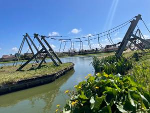 eine Hängebrücke über einen Fluss mit Blumen in der Unterkunft Bungalow Albatros in Julianadorp