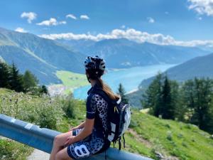 Eine Frau, die auf einer Schiene sitzt und die Berge ansieht. in der Unterkunft Alois Ferienglück in Nauders