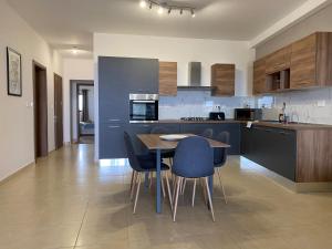 a kitchen with a table and blue chairs in it at Rabat Falcon Apartment in Rabat