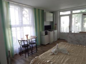 a bedroom with a bed and a table and a kitchen at Bori Apartmanok in Hajdúszoboszló