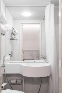 a white bathroom with a sink and a mirror at Omena Hotel Tampere in Tampere