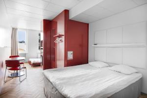a bedroom with a bed with a red wall at Omena Hotel Tampere in Tampere