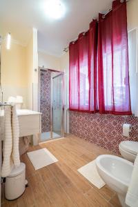 un bagno con due lavandini e una doccia con tende rosse di Musae Apartments ad Agropoli
