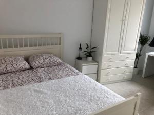 a white bedroom with a bed and a dresser at B&B Twiske Zuid, Amsterdam free parking in Amsterdam