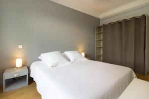 een slaapkamer met een groot wit bed en 2 lampen bij L'appartement à Cardaillac in Rodez