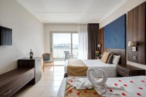 a hotel room with two beds with a swan decoration at Cavalieri Art Hotel in St. Julianʼs