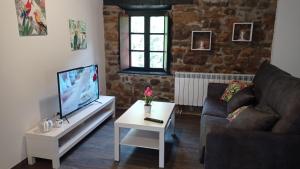 a living room with a couch and a tv and a table at Apartamentos la casa de los ríos in Liérganes