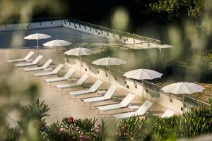 ローマにあるHotel Villa Pamphili Romaの白いラウンジチェアと傘
