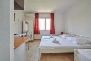 Habitación con 2 camas y cocina con cortinas rojas. en Apartments Balote, en Trogir