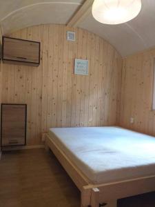 1 dormitorio con 1 cama en una habitación con paredes de madera en Osada nad żurawim stawem en Krzywogonice
