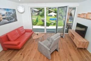 a living room with a red couch and a chair at Appartement Grimminggarten in Tauplitz