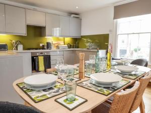 a kitchen with a wooden table with plates and glasses at Fairlight View in Folkestone