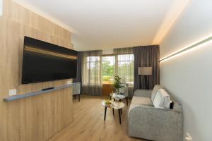 a living room with a couch and a flat screen tv at Cliff Hotel Rügen in Ostseebad Sellin