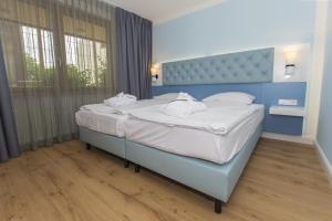 a bedroom with a blue bed with white sheets and pillows at Cliff Hotel Rügen in Ostseebad Sellin