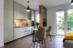 uma cozinha com armários brancos e uma mesa e cadeiras em Essence Apartments Sapphire em Poznań