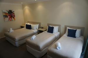 a hotel room with two beds and two couches at Lincoln Cottage Motor Inn in Wagga Wagga