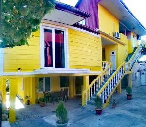 a yellow house with a staircase and a window at Kobuleti Guest House in K'obulet'i