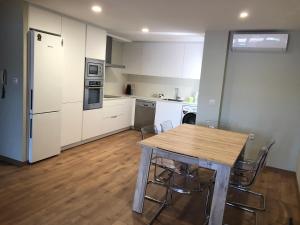 a kitchen with white cabinets and a wooden table and chairs at Apartamento en Rianxo in Rianjo +5 photos