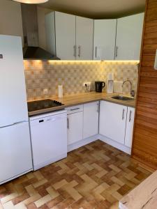kuchnia z białymi szafkami i drewnianą podłogą w obiekcie maison blanche w mieście Briançon