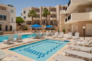 uma piscina com cadeiras e guarda-sóis em frente a um hotel em Orion Star em Agia Marina Nea Kydonias
