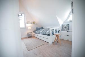 a white bedroom with a bed and a stool at Ferienhaus Emma in Kramerhof