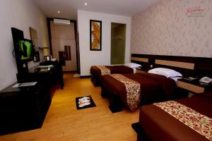 a hotel room with two beds and a flat screen tv at Kusuma Agrowisata Resort & Convention in Batu
