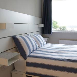 een slaapkamer met een bed met blauwe en witte lakens en een raam bij Crow's Nest Glandore - 1 - Self Catering in Glandore
