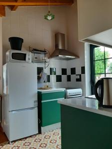 a kitchen with a white refrigerator and green cabinets at Beautiful house and garden at Serra da Estrela, perfect for groups and families in Gouveia