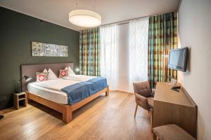 Schlafzimmer mit einem Bett, einem TV und einem Stuhl in der Unterkunft Hotel Bären am Bundesplatz in Bern